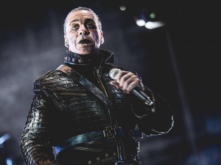 Der Sänger Till Lindemann düster geschminkt und mit Leder bekleidet steht auf der Bühne.