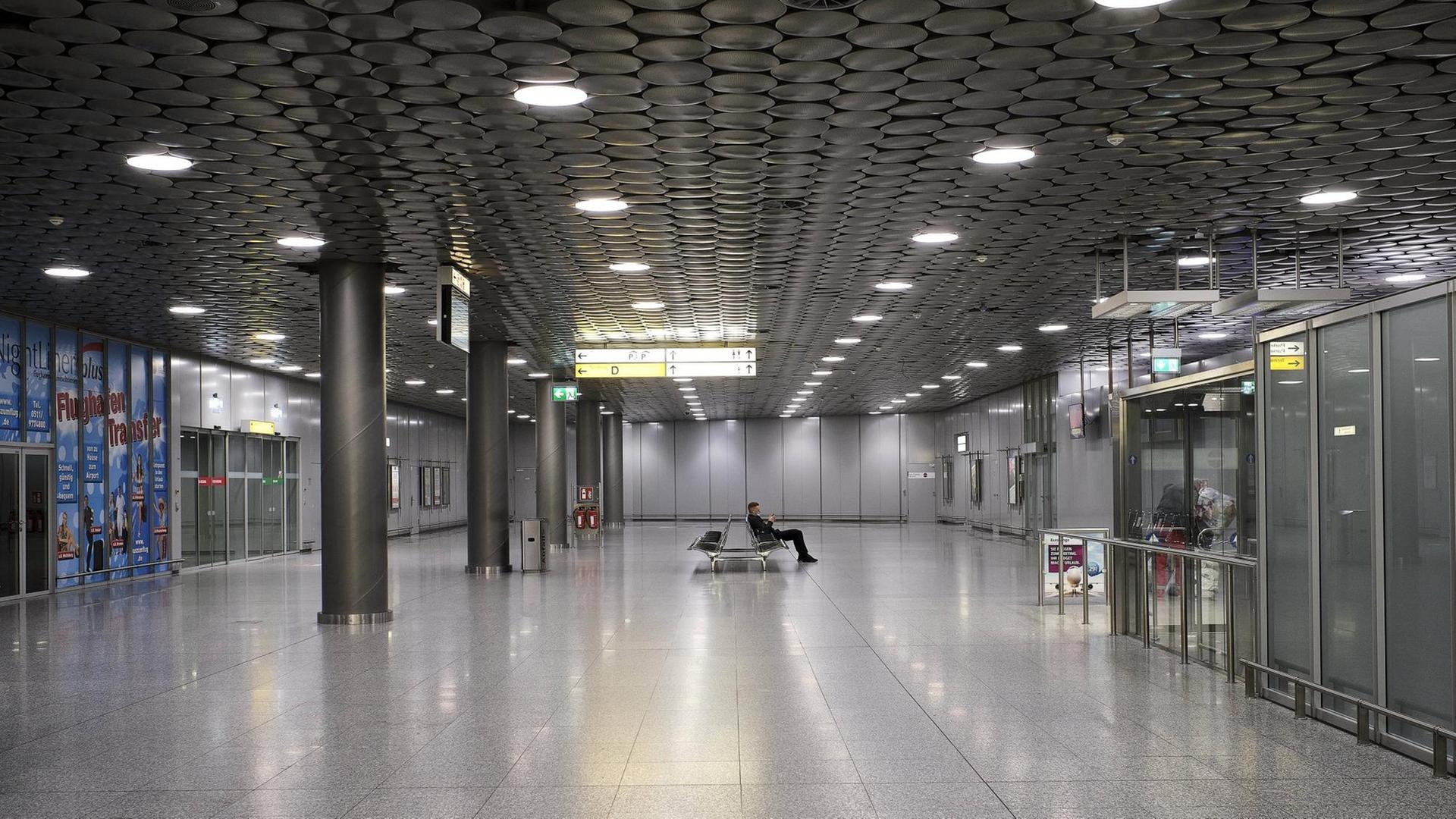 Eine bis auf einen einzelnen wartenden Mann leere Schalterhalle eines Flughafens