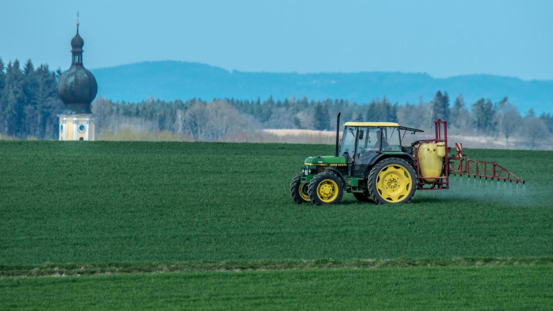 Mit einem Traktor wird am 14.04.2015 nahe Sallach im Landkreis Straubing-Bogen (Bayern) Pflanzenschutzmittel auf ein Feld gespritzt.