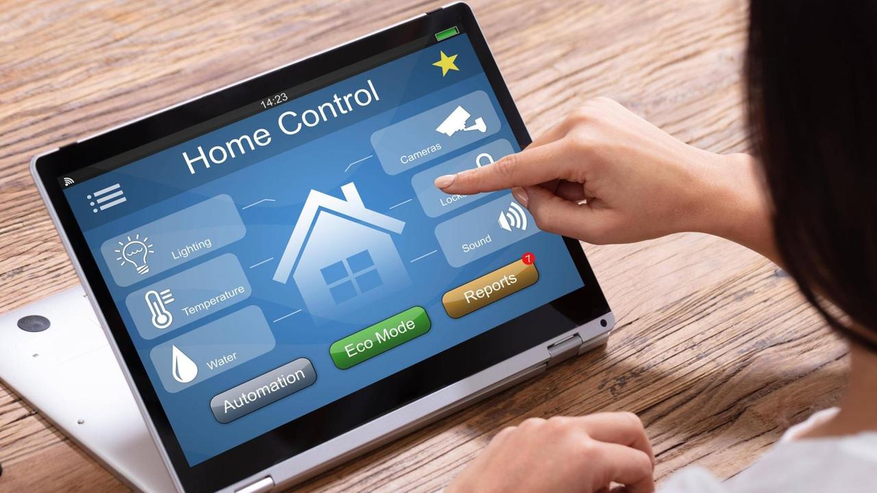 Frau bedient an einem Tablet ein Smart Home Control System für z.B.  Licht, Temperatur, Wasser, Überwachung