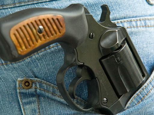 Ein Revolver Kaliber 9 mm ragt aus der Gesäßtasche einer Jeans-Hose