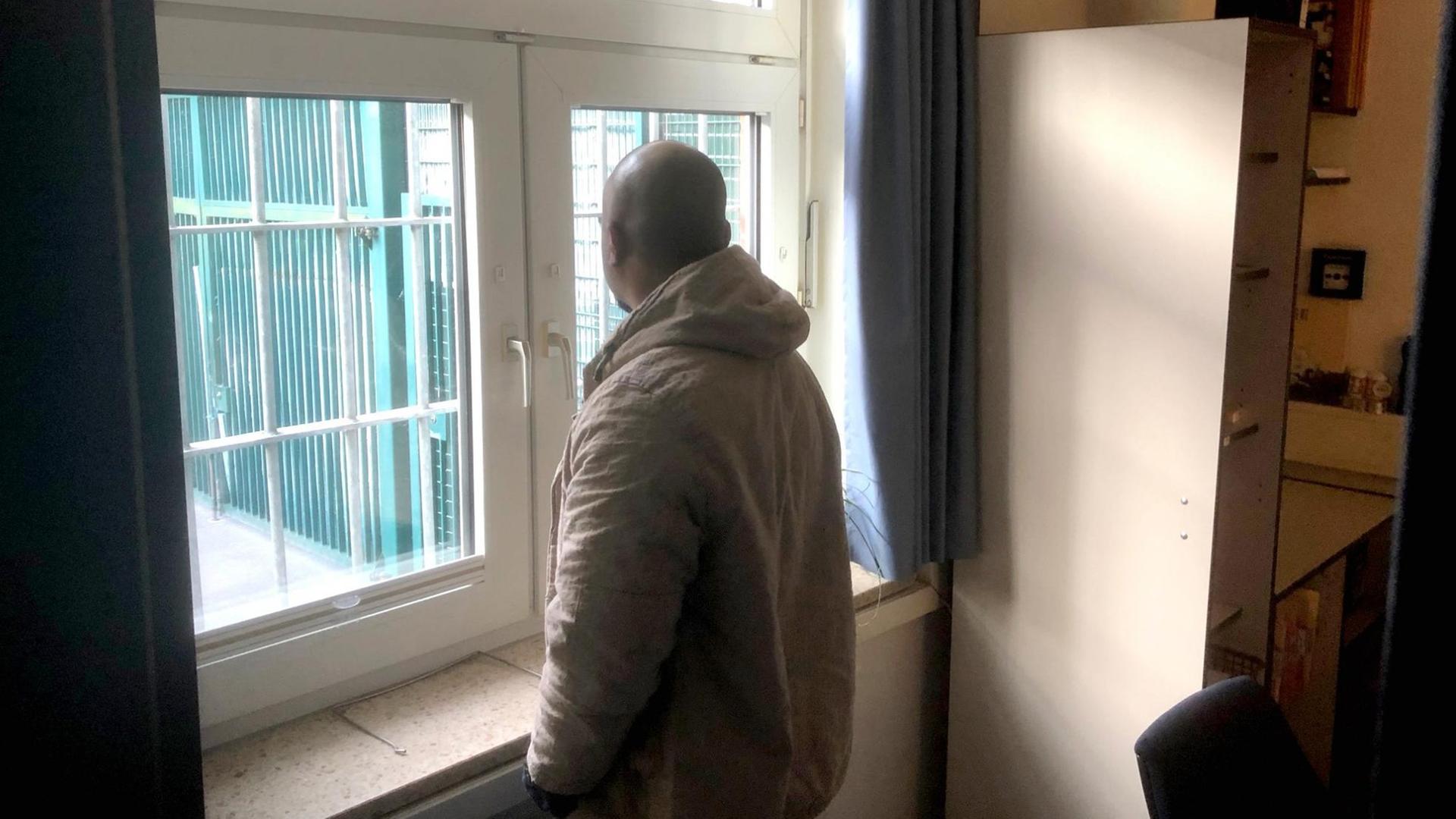 Ein Mensch in einem Abschiebe-Gefängnis schaut aus dem Fenster.
