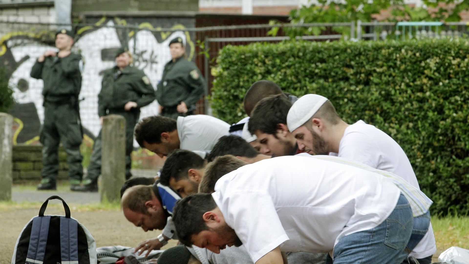Anhänger der Salafisten beten am Samstag (09.06.2012) in Köln unter der Beobachtung der Polizei.
