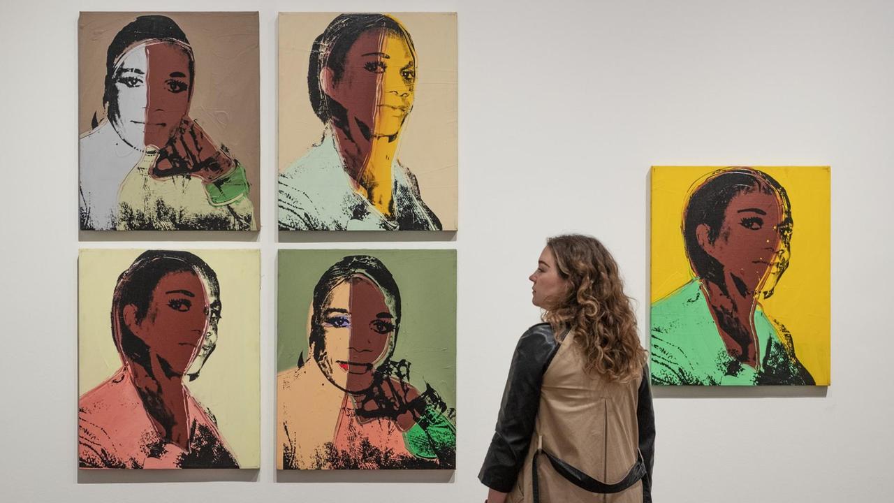 Eine Mitarbeiterin der Galerie Tate Modern betrachtet das Bild "Alphanso Panell" aus der Serie "Ladies and Gentlemen" (1975) von Andy Warhol.