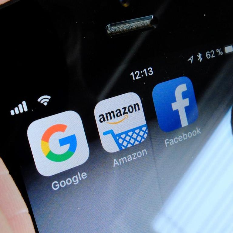 Die Logos der US-Internetkonzerne Google (l-r), Amazon und Facebook sind auf dem Display eines iPhone zu sehen.