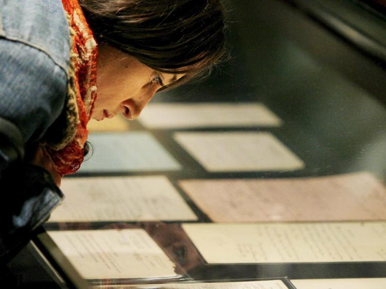 Eine junge Frau beugt sich über Briefe und Dokumente von Otto Frank, Vater von Anne Frank.