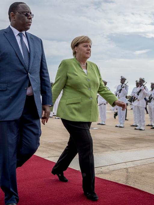 Bundeskanzlerin Angela Merkel (CDU) wird von Macky Sall, dem Präsidenten der Republik Senegal, am Flughafen begrüßt.