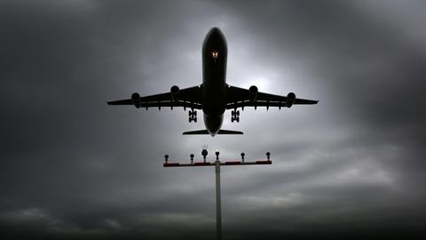 Ein Flugzeug beim Landevorgang am Flughafen Frankfurt vor düster grauem Himmel.