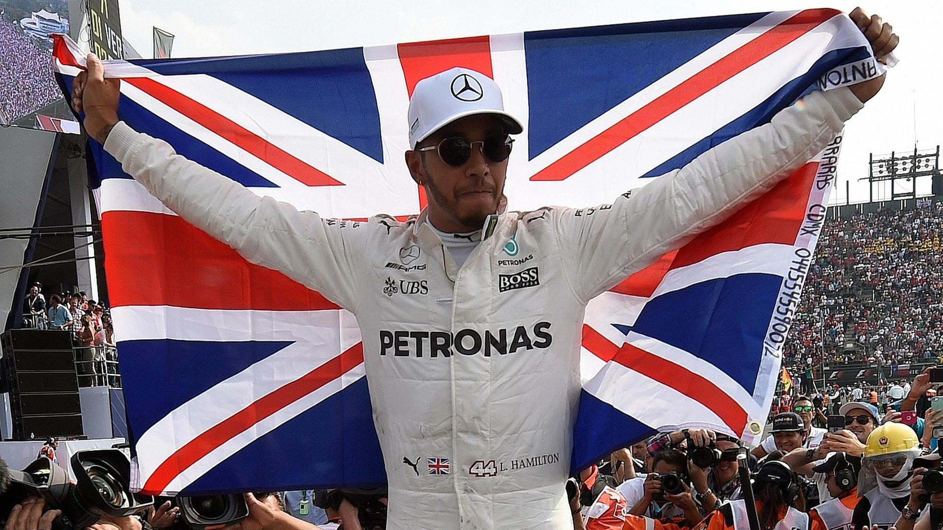 Hamilton hält eine große britische Flagge hoch.
