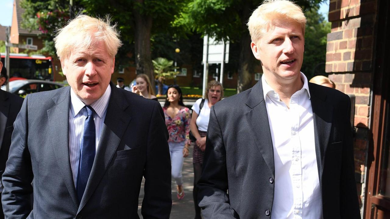 Die beiden Brüder Boris und Jo Johnson laufen nebeneinander. Beide tragen einen dunklen Anzug und ein helles Hemd.