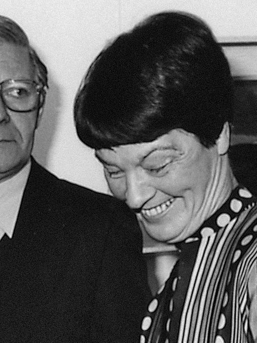 Helmut Schmidt steht vor einem Gemälde, eine Hand in der Hosentasche, Loki Schmidt steht lachend daneben