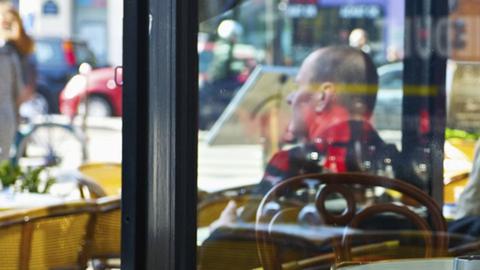 Ein Mann im Café, aus dem Fenster blickend.