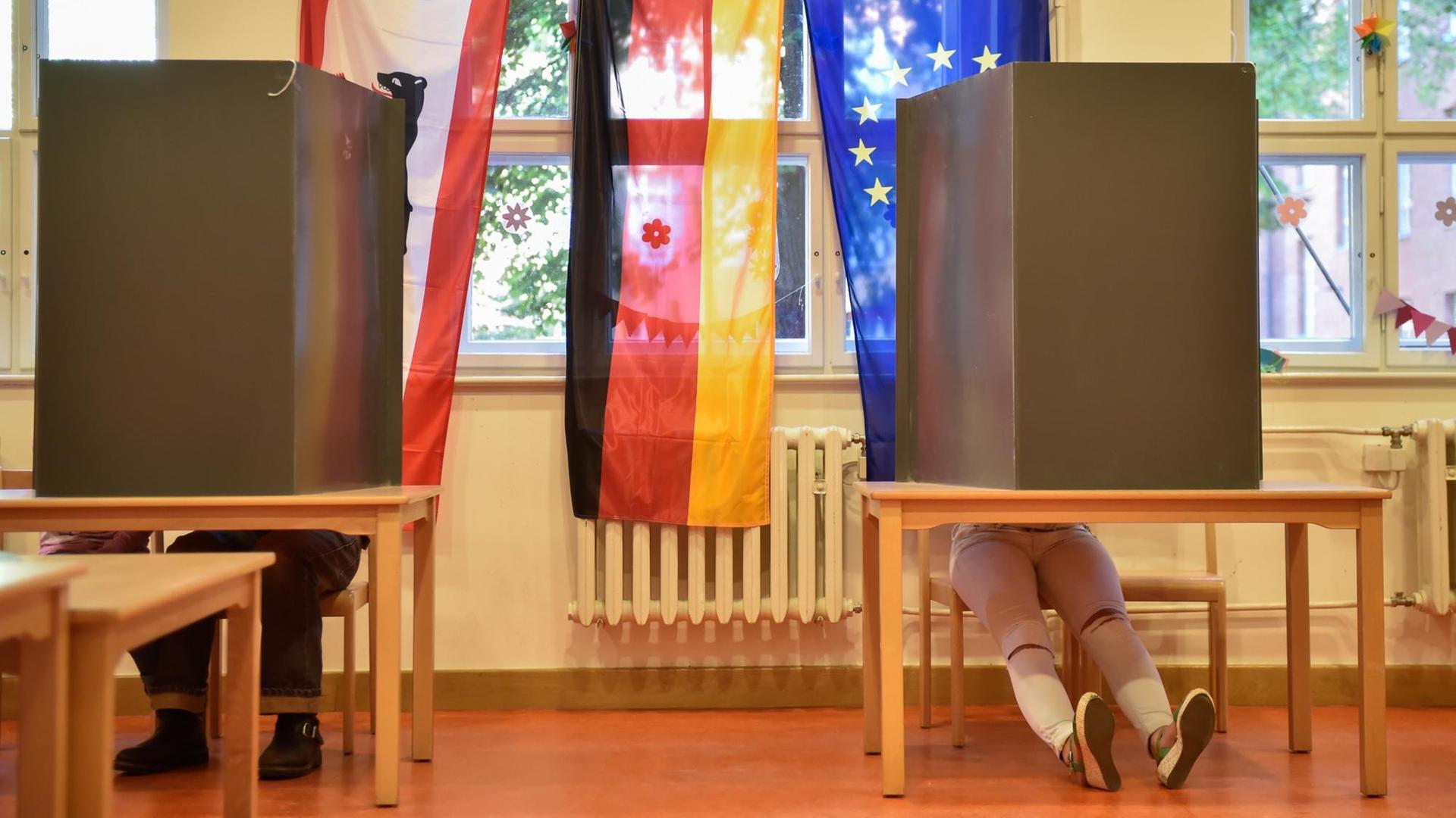 Wähler sitzen am 18.09.2016 bei der Abgeordnetenhauswahl in Berlin in einem Wahllokal in der Wahlkabine.