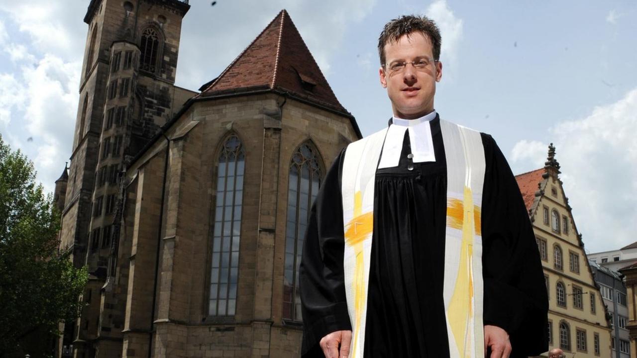Pfarrer Matthias Vosseler steht mit Laufschuhen vor der evangelischen Stiftskirche in Stuttgart