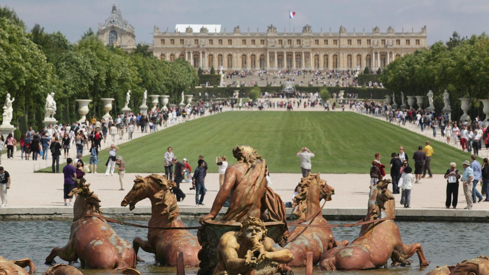 Das Bild zeigt die Gartenfassade des Schlosses von Versailles, im Vordergrund der Apollo-Brunnen.