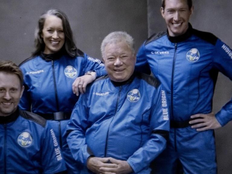 William Shatner mit den anderen Astronauten in blauen Anzügen.