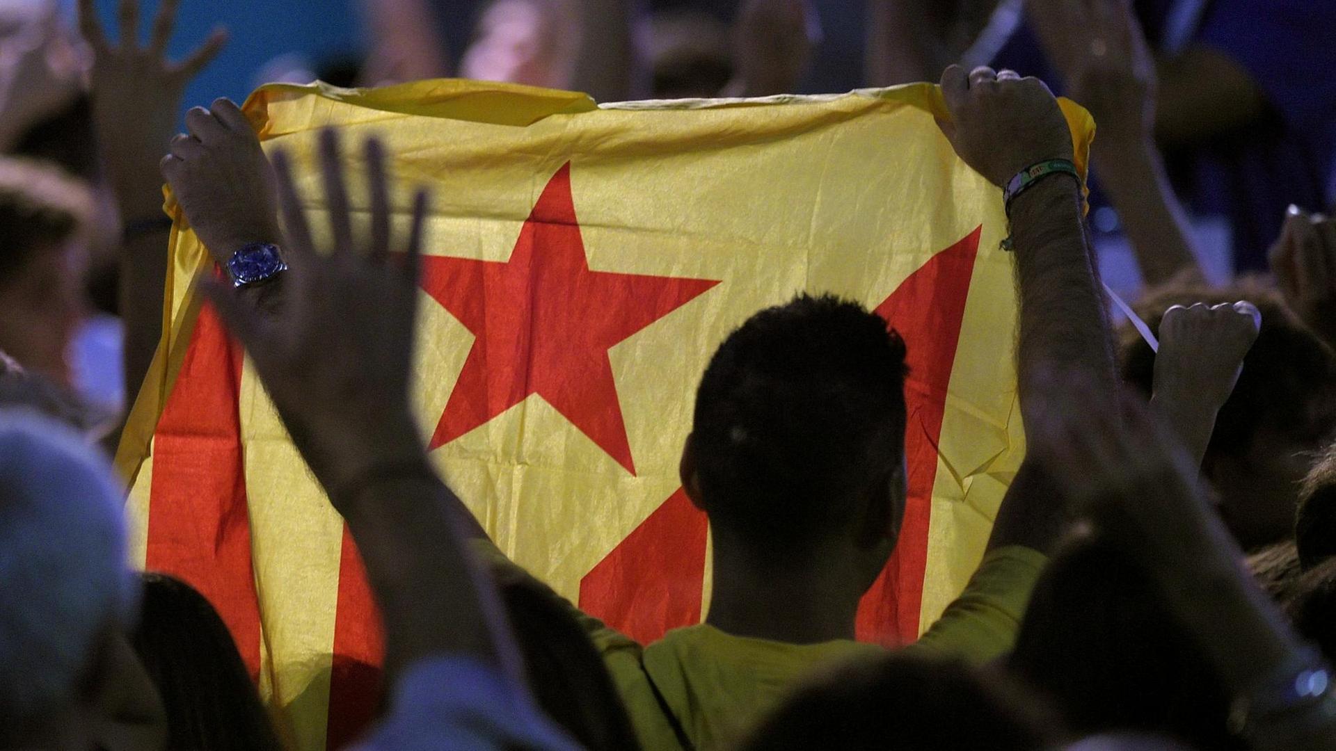 Ein Mann in Barcelona hält bei der Regionalwahl eine katalanische Flagge hoch, um für die Unabhängigkeit Kataloniens zu demonstrieren.