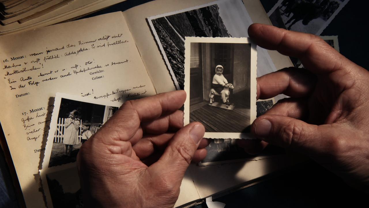 Markus Imhoof hält ein altes Foto in den Händen.