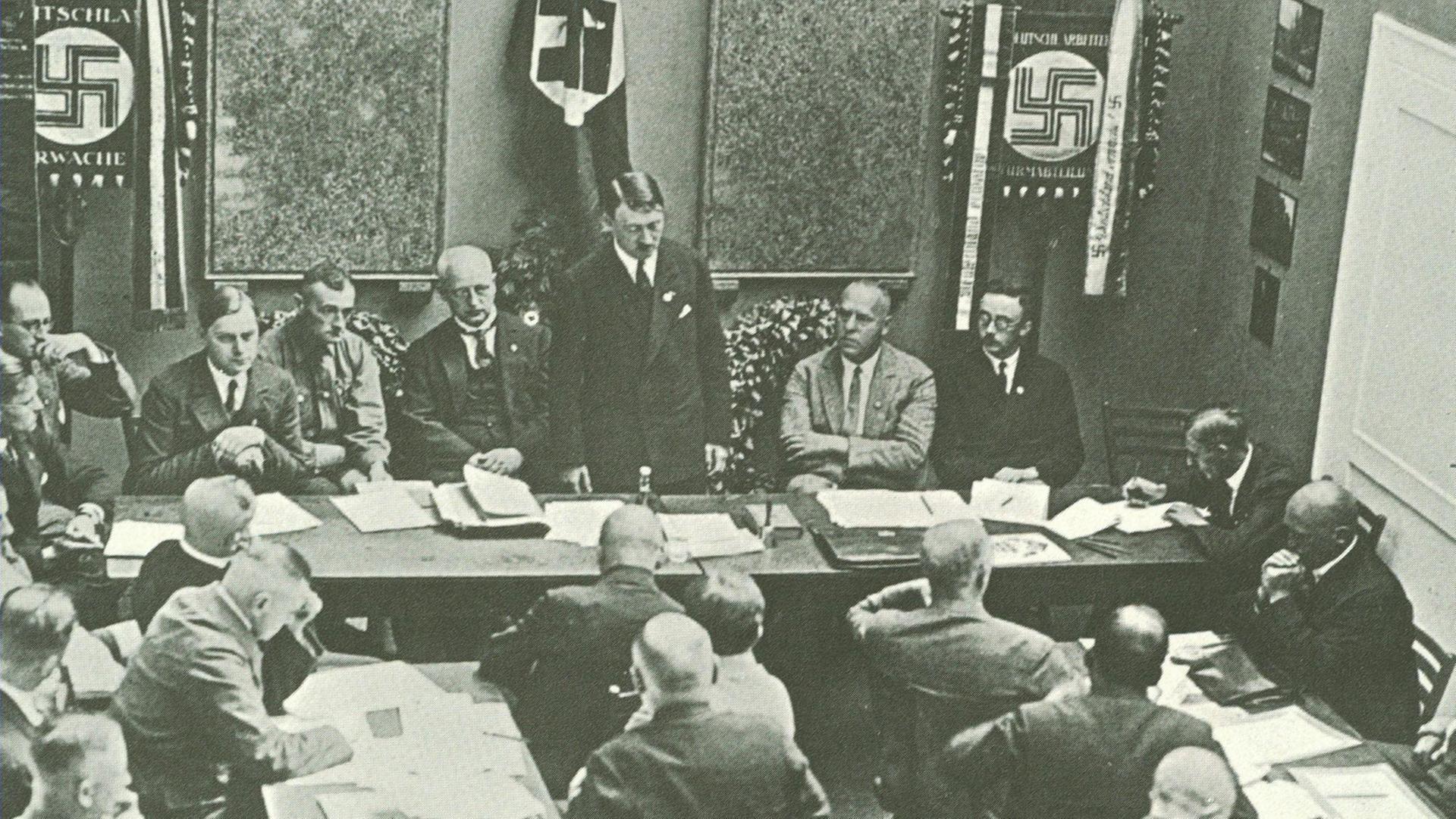 Hitler in Munich adressing a meeting of the NSDAP in 1925. Third to the left of Hitler is Alfred Rosenberg, on the right are Gregor Strasser and Heinrich Himmler. Far right by the door is Julius Streicher. | Verwendung weltweit, Keine Weitergabe an Wiederverkäufer.