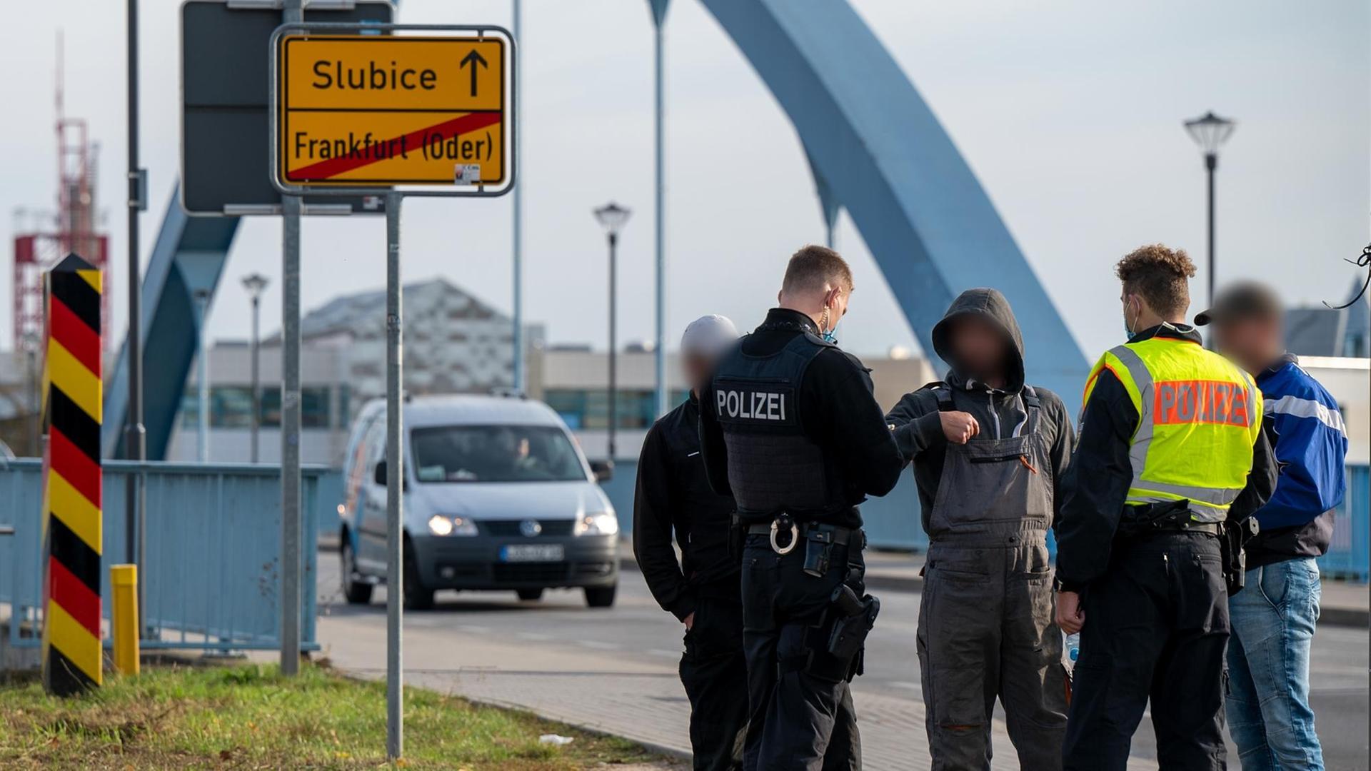 Zwei Polizisten kontrollieren auf der Grenzbrücke nach Slubice, Polen, drei Männer, die die Grenze zu Fuß überquerten.