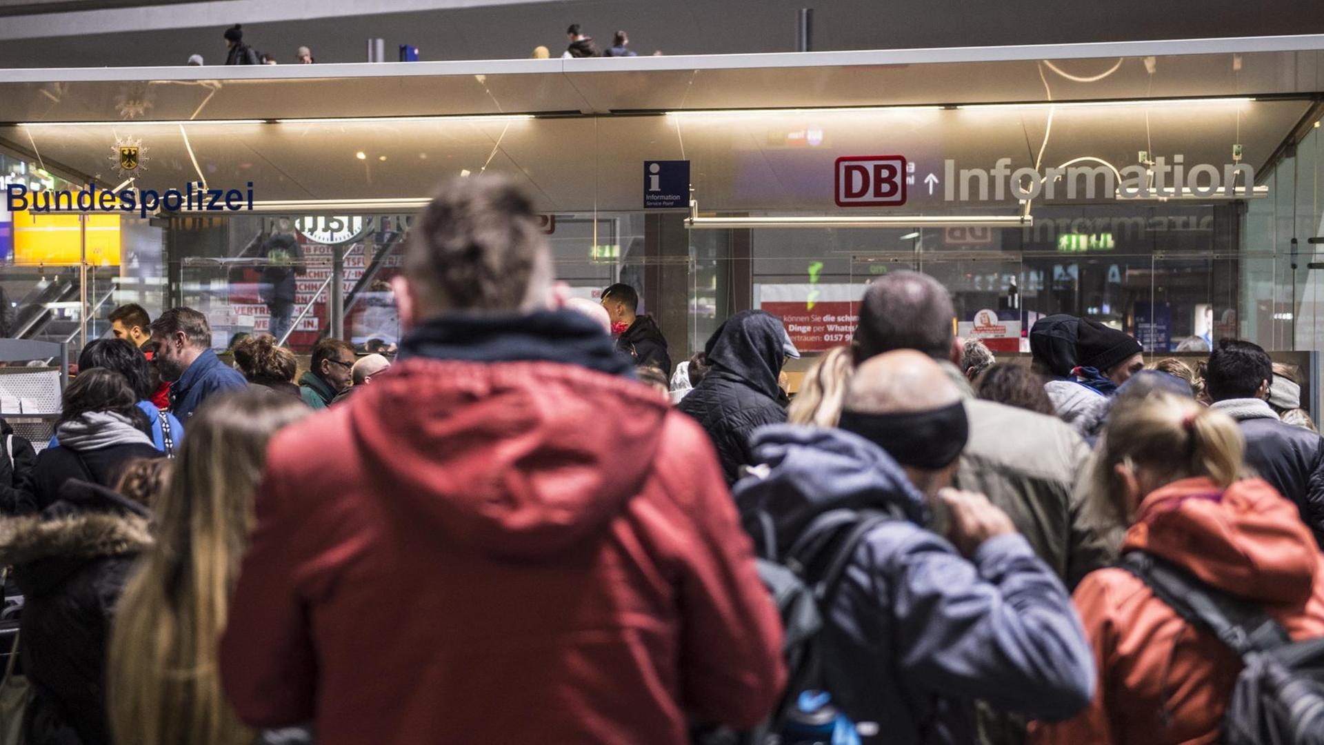 Reisende warten an einem Schalter der Deutschen Bahn
