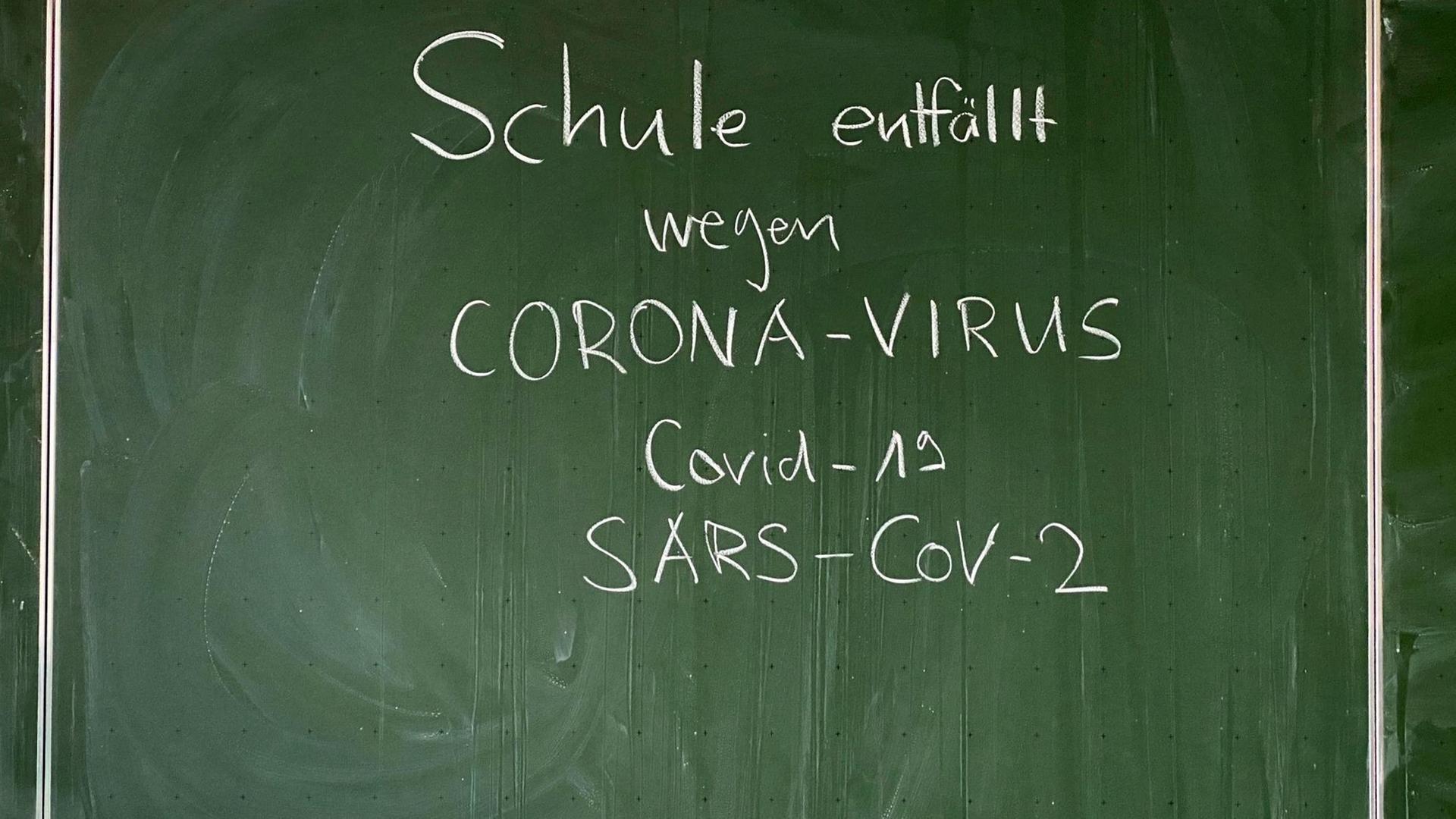 Auf einer Tafel steht geschrieben: Schule entfällt wegen Corona-Virus, Covid-19, SARS-CoV-2