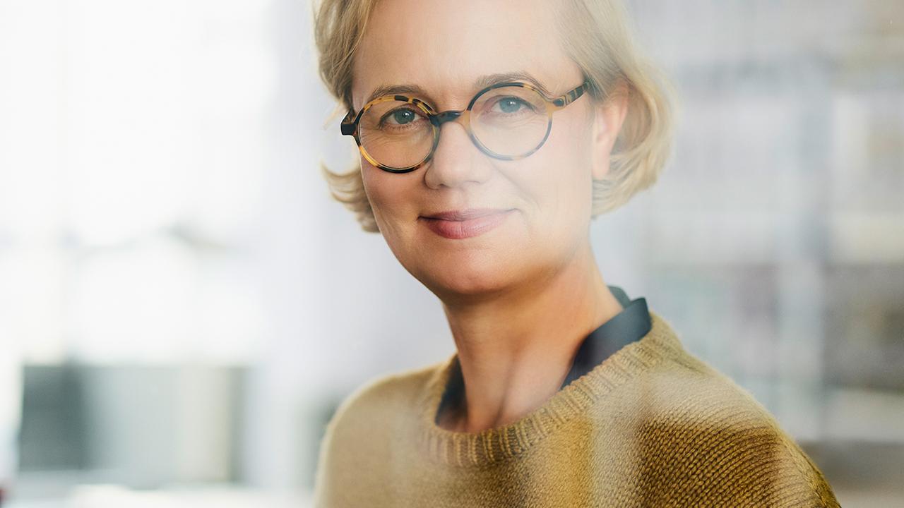 Die Geschäftsführerin der Uhrenfirma Nomos aus Glashütte in Sachsen, Judith Borowski, steht hinter eine Scheibe und lächelt in die Kamera.