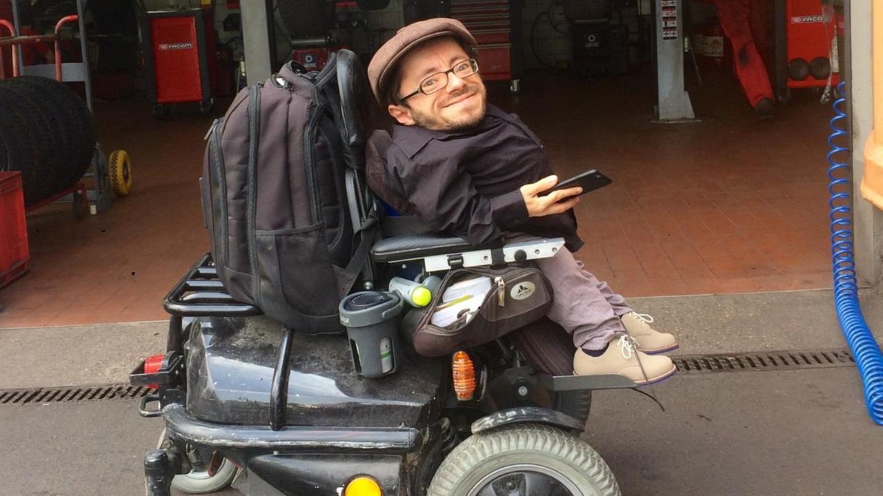 Der Behinderten-Aktivist Raul Krauthausen lässt seinen platten Rollstuhlreifen in der Autowerkstatt reparieren.