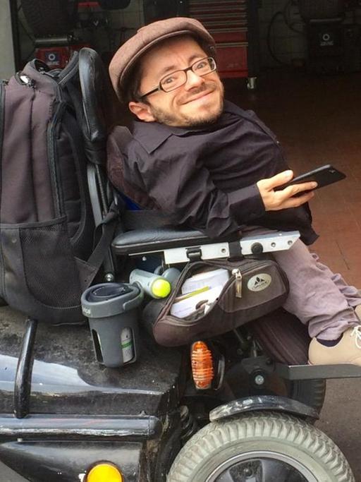 Der Behinderten-Aktivist Raul Krauthausen lässt seinen platten Rollstuhlreifen in der Autowerkstatt reparieren.