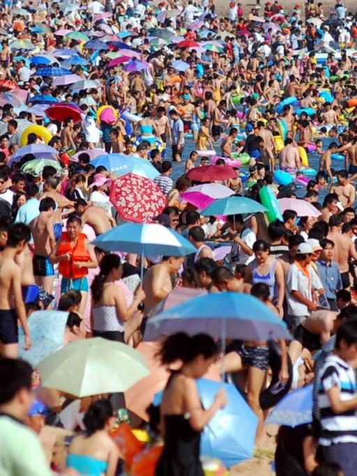 Sehr viele Menschen drängen sich am Strand in der Bucht bei Qingdao (China).