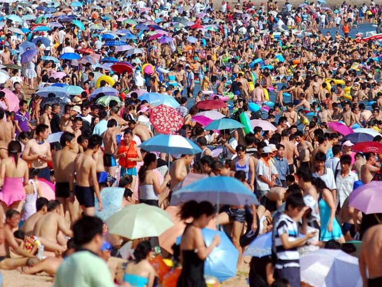 Sehr viele Menschen drängen sich am Strand in der Bucht bei Qingdao (China).