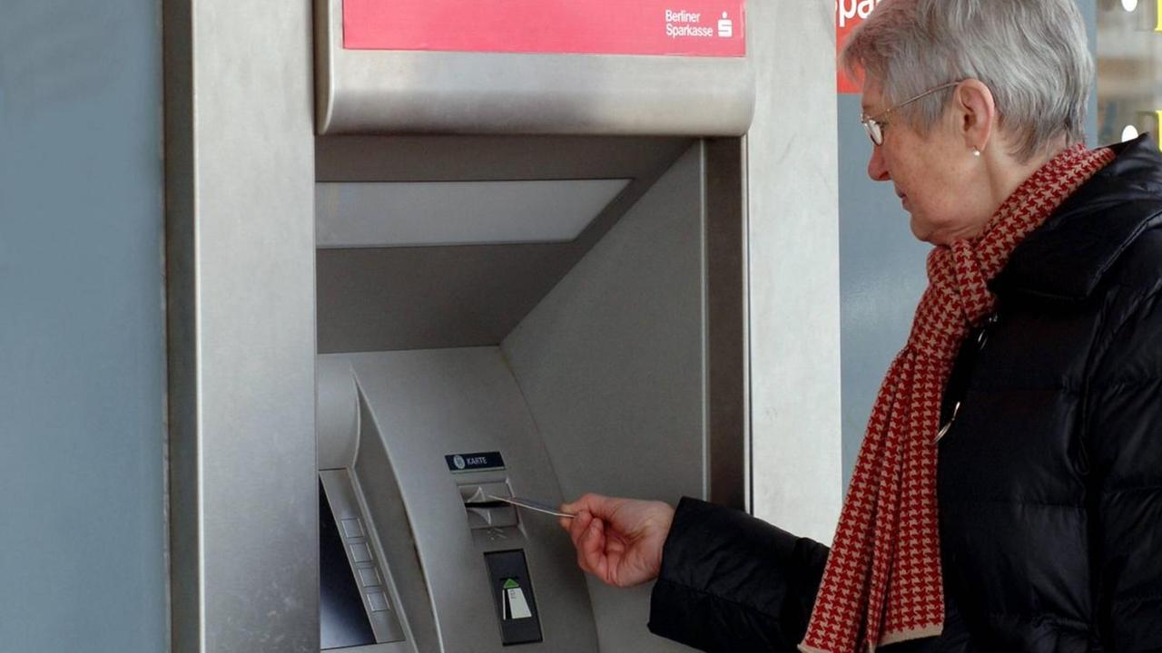 Eine Rentnerin hebt am Geldautomaten Geld ab