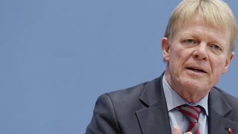 Reiner Hoffmann sitzt auf dem Podium und spricht.