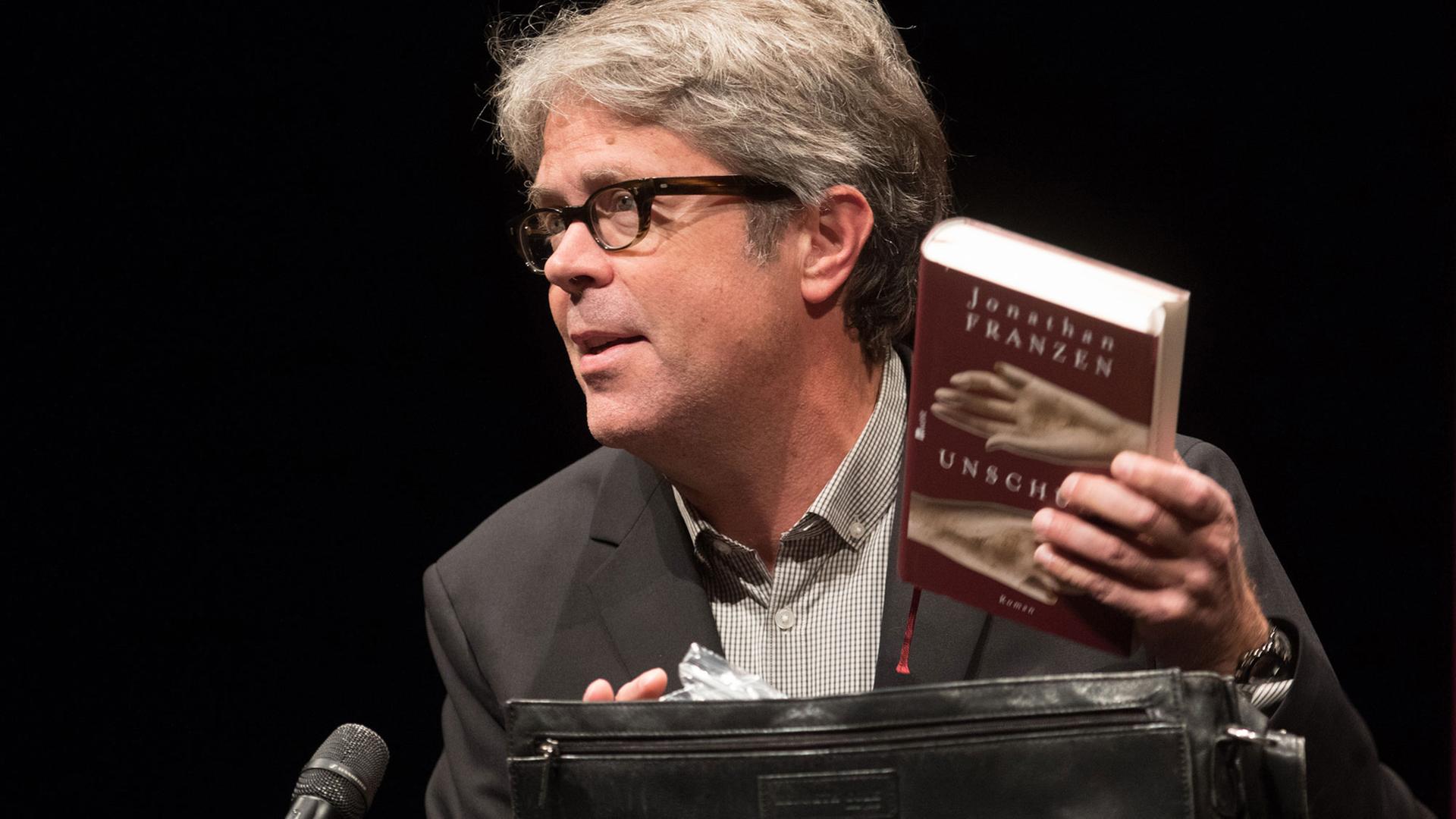 Der US-amerikanische Bestseller-Autor Jonathan Franzen zieht am 08.10.2015 in Hamburg auf der Bühne des Thalia Theaters seinen Roman "Unschuld" aus einer Aktentasche.
