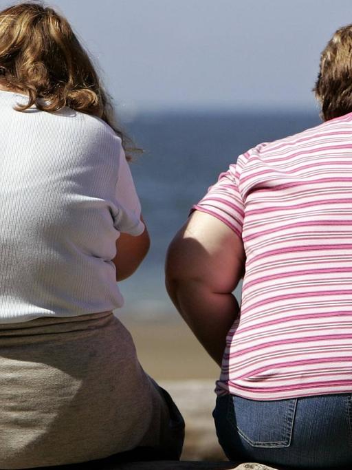 Zwei übergewichtige Menschen am Strand.
