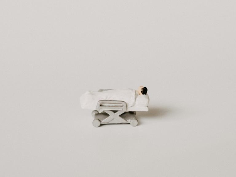 Miniaturfigur einer bettlägerigen Person