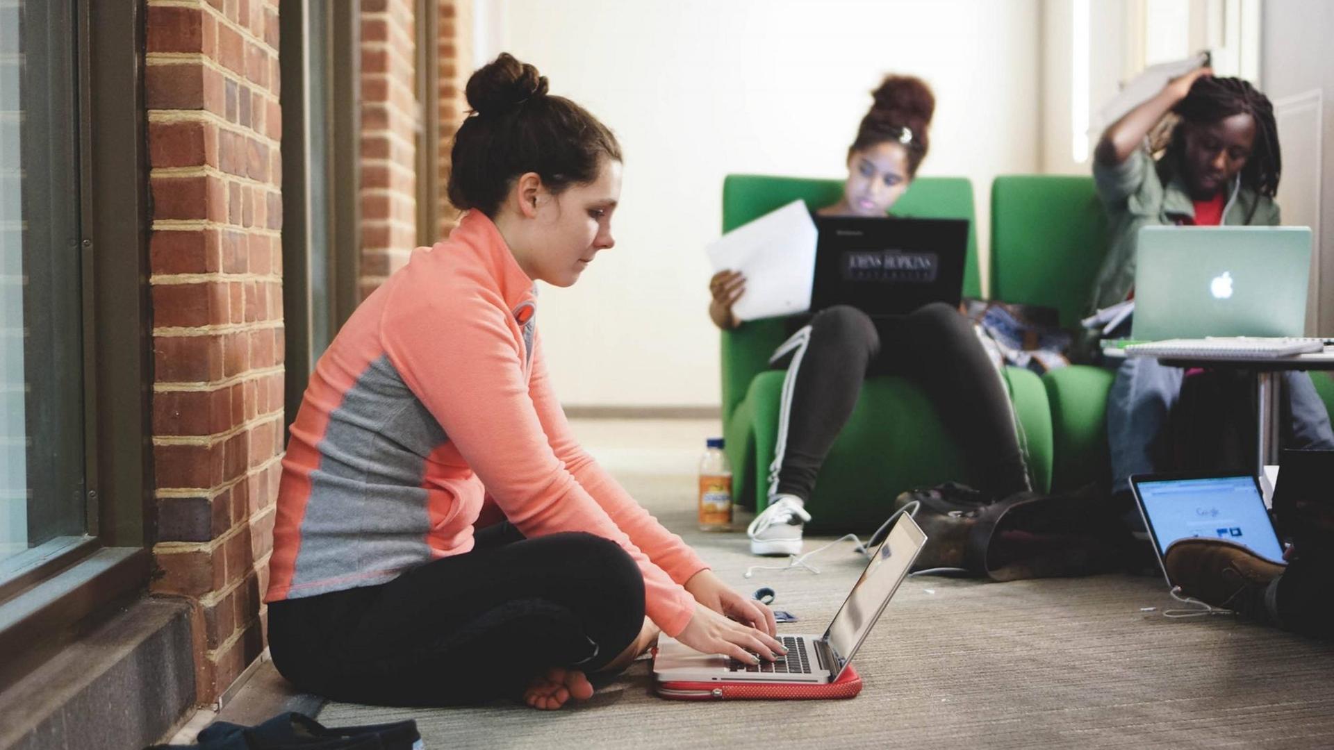 Studenten sitzen mit ihren Laptops auf Sesseln und auf dem Boden auf dem Campus ofder Johns Hopkins University in Baltimore im US-Staat Maryland, aufgenommen 2015