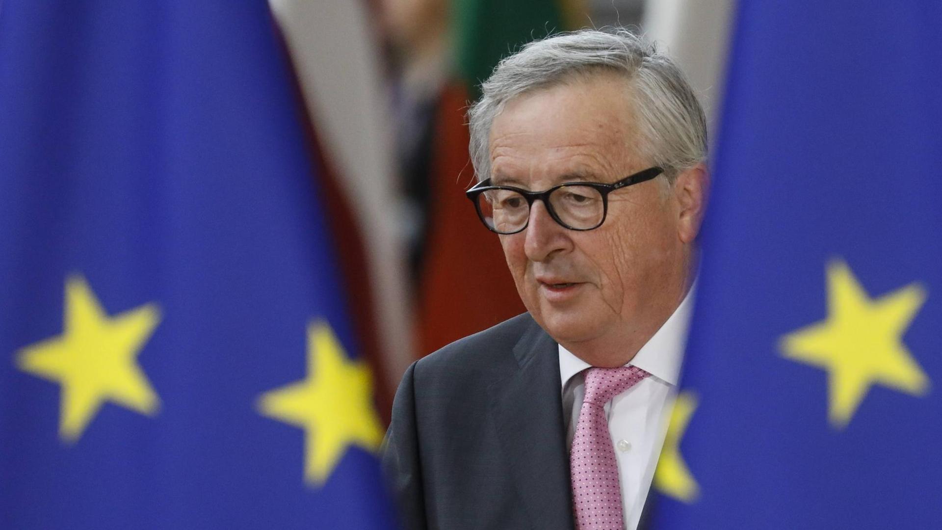 Der scheidende EU-Kommissionspräsident Jean-Claude Juncker erscheint zwischen zwei EU-Flaggen in Brüssel