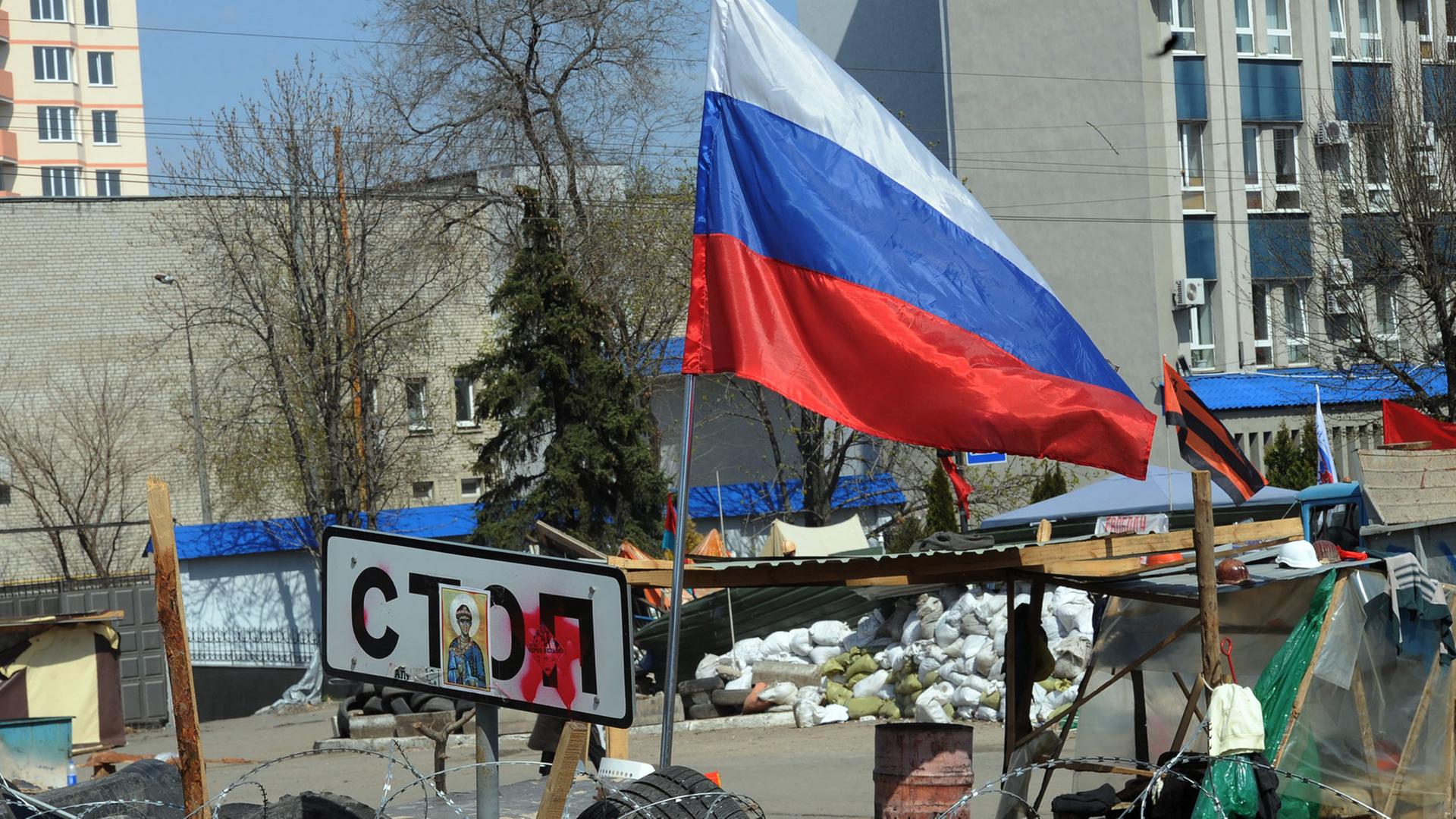 Barrikade aus Autoreifen, darauf ein Stop-Schild und eine russische Fahne.