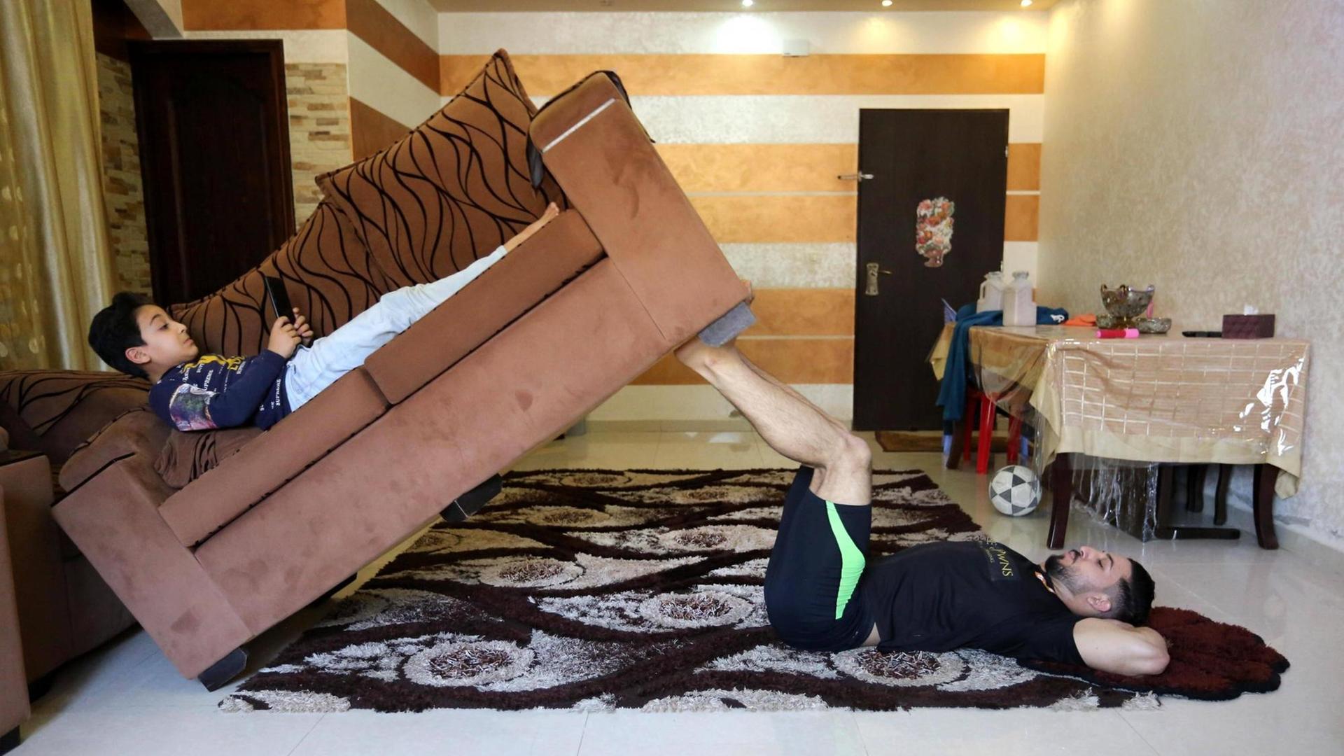 Im Gaza Streifen trainiert der palestinensische Fitnesstrainer and Bodybuilder, Ahmed al-Sawi, indem er die Wohnzimmer Couch mit seinem Sohn darauf stemmt.