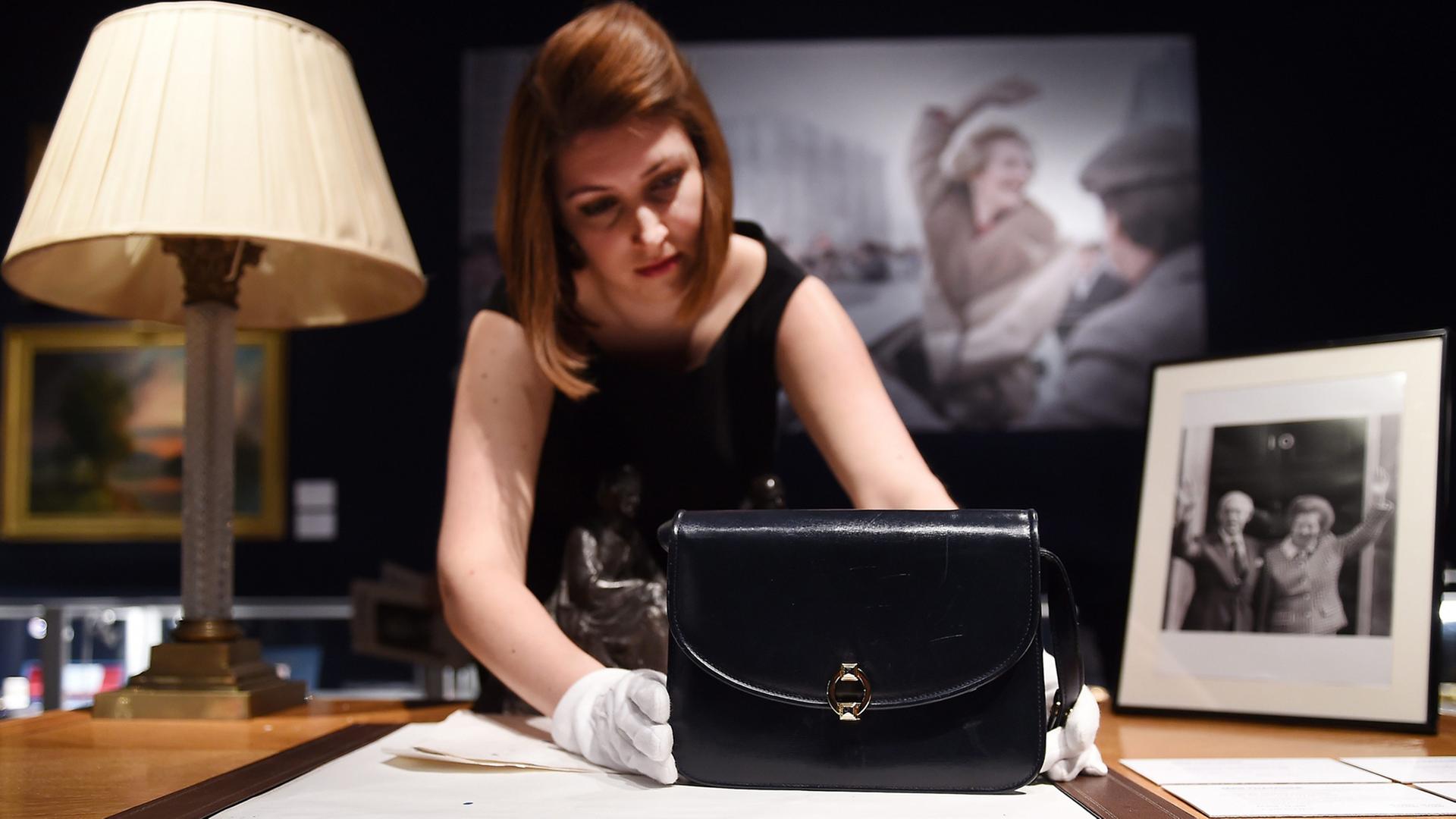 Eine Mitarbeiterin von Christie's präsentiert eine Handtasche von Margaret Thatcher. Über 400 Objekte aus dem Nachlass der britischen Premierministerin werden im Auktionshaus versteigert.