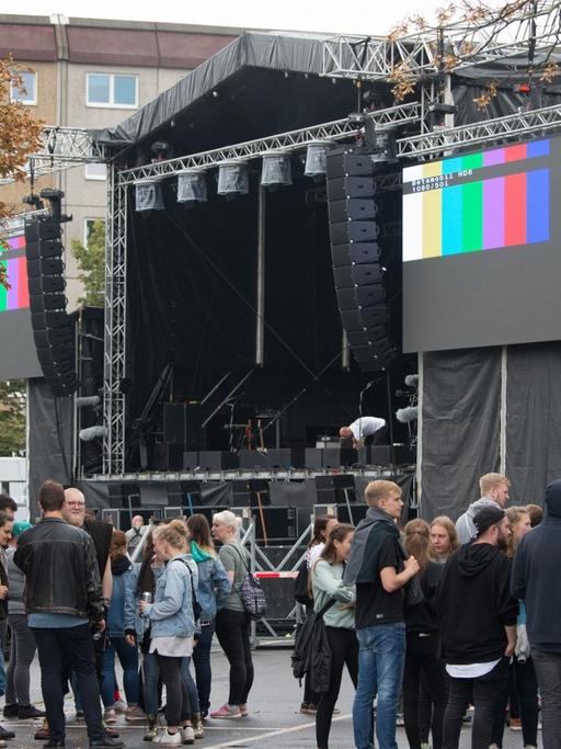 03.09.2018, Sachsen, Chemnitz: Konzertbesucher warten auf dem Parkplatz an der Johanniskirche hinter einer Absperrung vor der Bühne auf den Beginn des Konzerts.