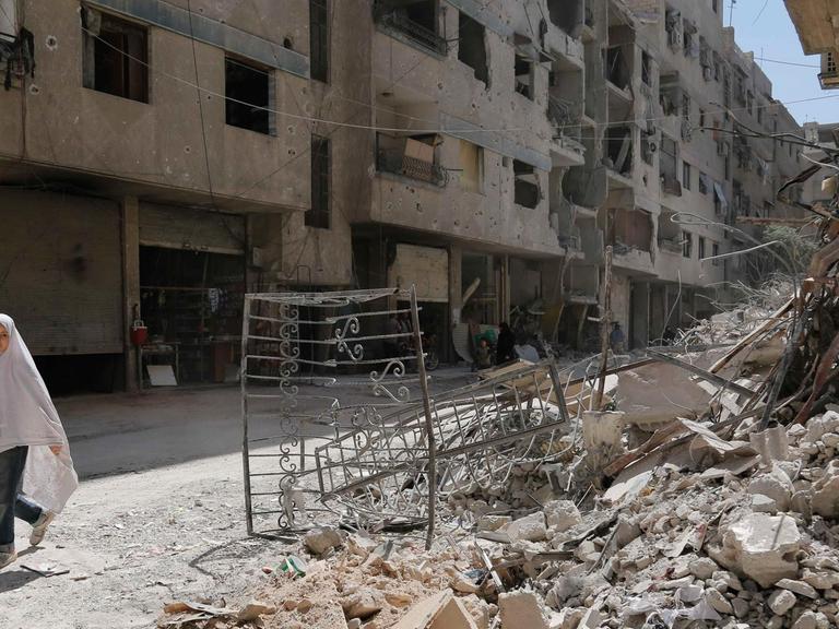 in Mädchen geht durch eine zerstörte Straße in der Stadt Ayn Tarma in der Region Ghouta östlich von Damaskus