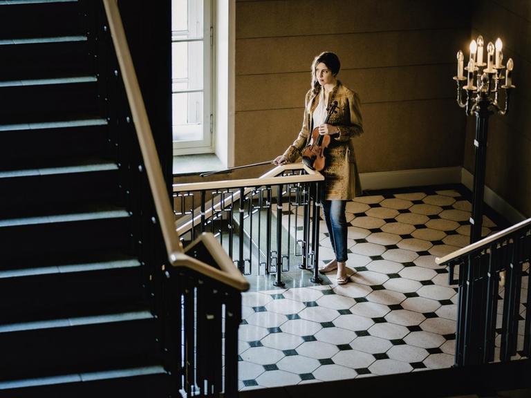 Vilde Frang steht mit Geige und Bogen im Treppenhaus