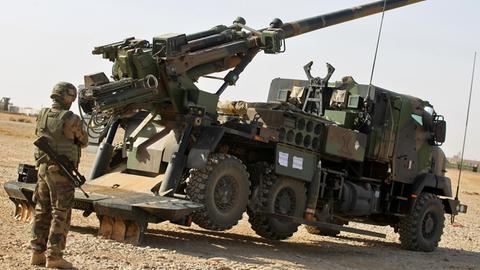 Ein Soldat steht hinter einem Haubitzen-Fahrzeug vom Typ "Caesar". Die Kanone ist schussbereit aufgerichtet.