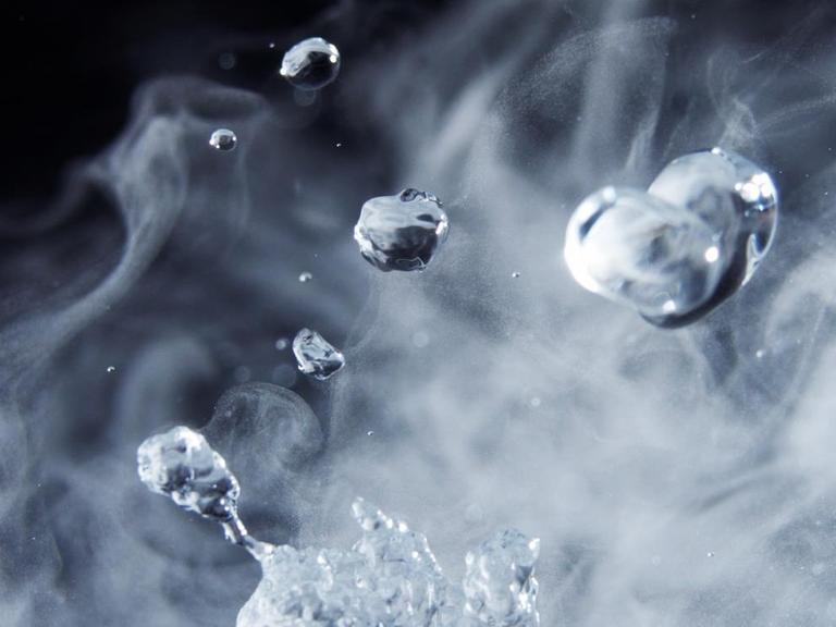 Nahaufnahme der verschiedenen Aggregatzustände von Wasser, in flüssiger Tropfenform und als Wasserdampf.
