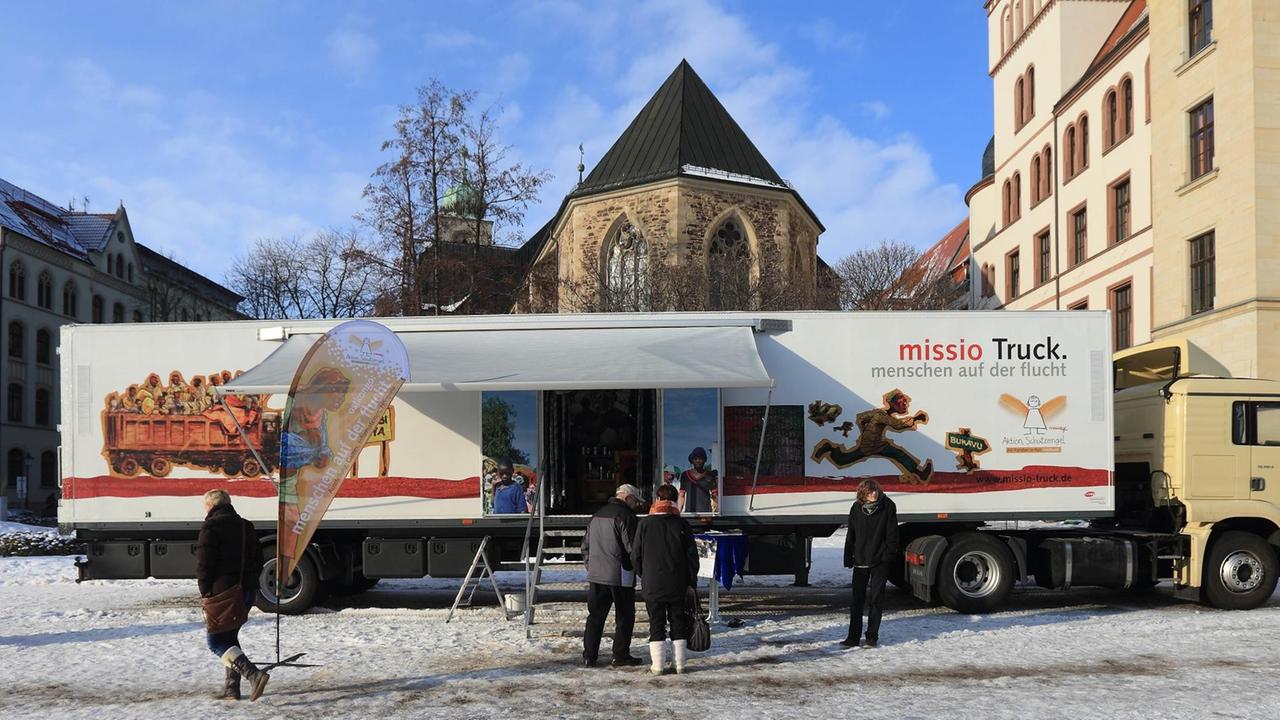 Menschen stehen vor dem missio-Truck mit der Ausstellung "Menschen auf der Flucht".