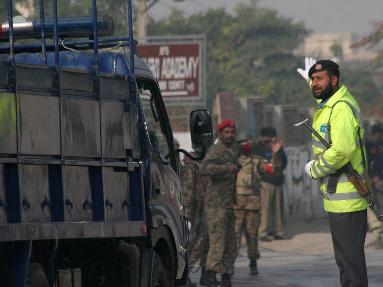 Pakistanische Sicherheitskräfte weisen einem Rettungsfahrzeug in Peschawar den Weg.