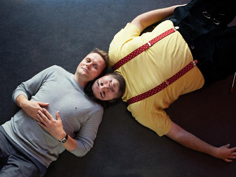 Devid Striesow und Axel Ranisch liegen auf dem Boden, die Köpfe nebeneinander