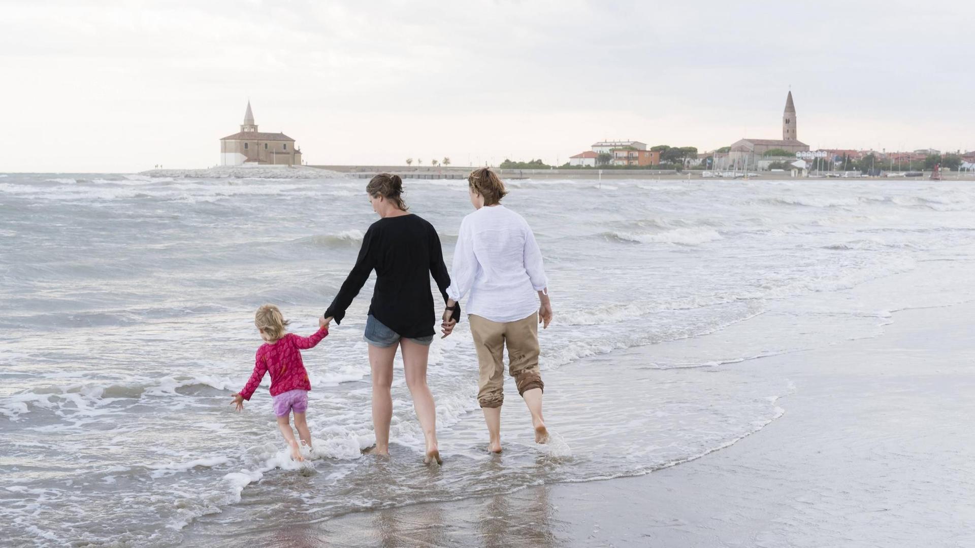 Zwei Frauen spazieren mit einem Kind am Strand. Zwei Frauen spazieren mit einem Kind am Strand.